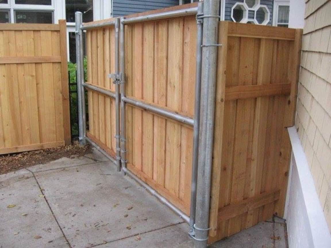 Cedar-faced driveway gate with a metal frame installed across a concrete driveway