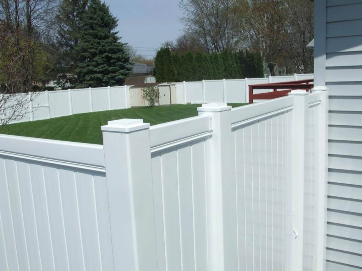 White vinyl PVC privacy fence enclosing a residential backyard lawn